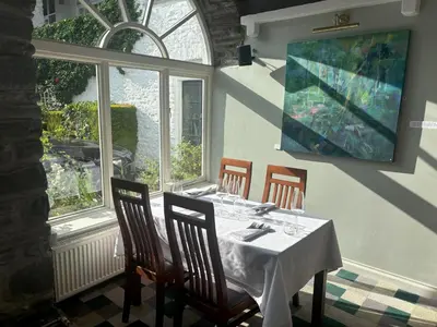 a dining room with a table and chairs and windows at Feathers Hotel Bar and Restaurant in Aberaeron