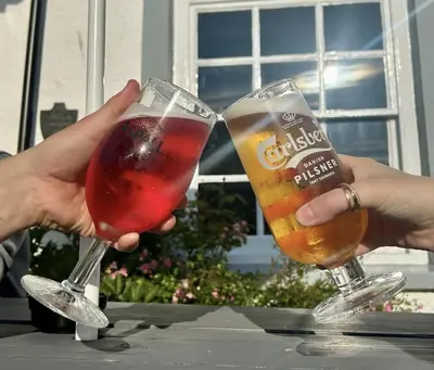 two people are holding glasses of drinks on a table at Feathers Hotel Bar and Restaurant in Aberaeron