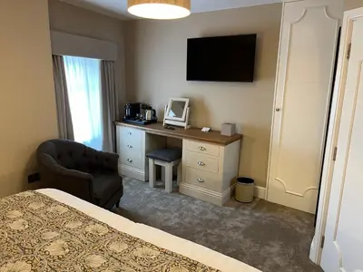 a bedroom with a desk and a chair and a television at The Castle Coaching Inn in Trecastle