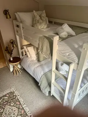 two white bunk beds in a room with a rug at Posh Little Cottage in Llangollen