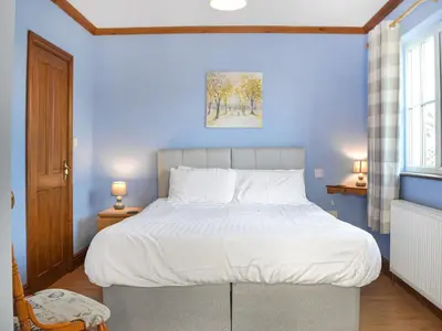 a bedroom with a large bed with a blue wall at Ferwig in New Quay