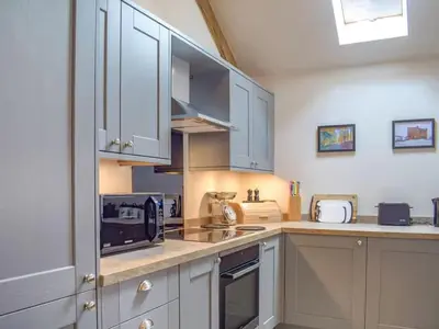 a kitchen with white cabinets and a counter top at Castle Beams in Craven Arms
