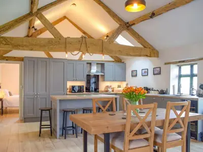a large kitchen with a wooden table and chairs at Castle Beams in Craven Arms