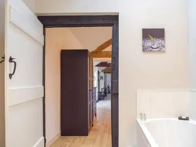 a bathroom with a bath tub and a hallway at Castle Beams in Craven Arms