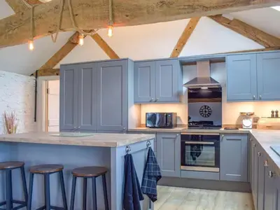 a kitchen with blue cabinets and bar stools at Castle Beams in Craven Arms