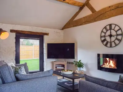 a living room with a fireplace and a tv at Castle Beams in Craven Arms