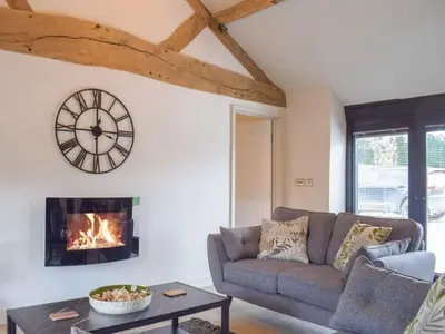 a living room with a couch and a clock on the wall at Castle Beams in Craven Arms