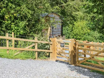 a wooden fence with a gate next to a bush at Shepherd's Cwtch in Llandovery