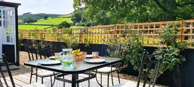 a table and chairs on a patio with a fence at Awelfa a peaceful cottage in the Cambrian mountains in Llanbrynmair