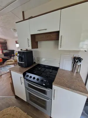 a kitchen with a stove and white cabinets at Stunning Pet Friendly 2 bed StaticCaravan in Clarach Bay 2017 model in Aberystwyth