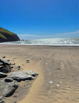 a sandy beach with rocks and the ocean at Stunning Pet Friendly 2 bed StaticCaravan in Clarach Bay 2017 model in Aberystwyth