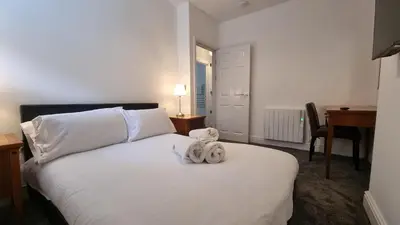 a bedroom with a white bed with towels on it at Abergwaun Apt 2 in Aberystwyth