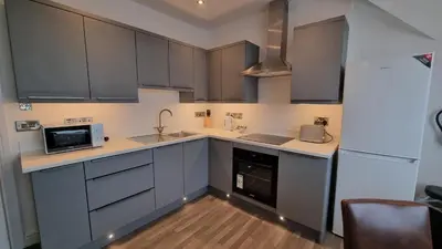 a kitchen with gray cabinets and a white refrigerator at Abergwaun Apt 2 in Aberystwyth