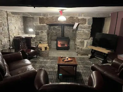 a living room with leather furniture and a stone fireplace at Maes Y Neuadd Country House in Talsarnau