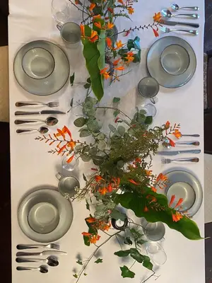 a table with plates and utensils and a flower arrangement at Maes Y Neuadd Country House in Talsarnau