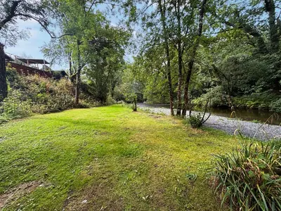 a field of grass next to a river with trees at The Squirrels Drey C32 - Uk45927 in Newtown