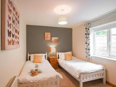 two twin beds in a room with two windows at High Tide in Scyborycoed