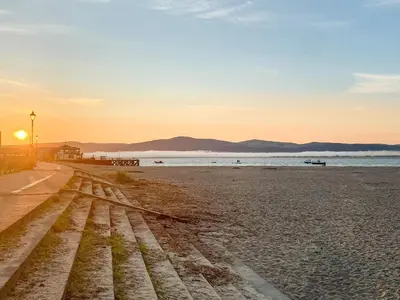 a beach with the sun setting over the water at High Tide in Scyborycoed