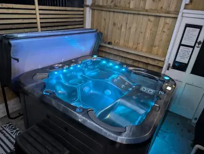 a jacuzzi tub with blue liquid inside of it at Synod Farm Cottage, 5 Person Hot Tub, Pets Welcome in Llandysul