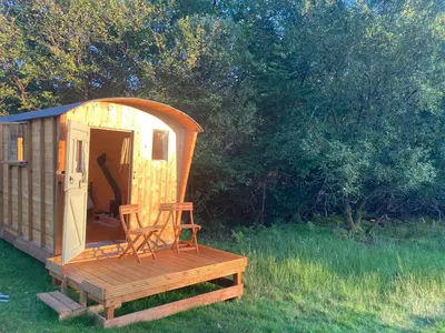 a wooden cabin with a chair sitting on a deck at Shepherds Hut on Alpaca and working farm in Blaenau-Ffestiniog
