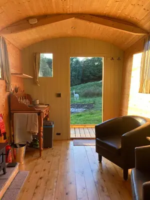 a living room with a door open to a yard at Shepherds Hut on Alpaca and working farm in Blaenau-Ffestiniog