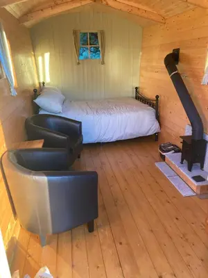 a bedroom with a bed and a chair in a cabin at Shepherds Hut on Alpaca and working farm in Blaenau-Ffestiniog