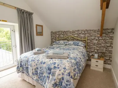a bedroom with a bed and a stone wall at Garden View in Llanybydder