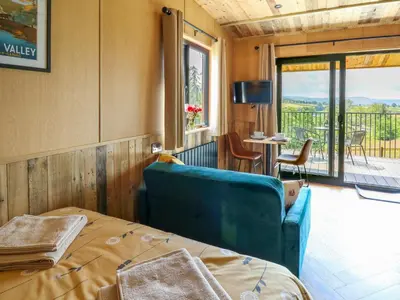 a room with a bed and a couch and a balcony at Rooster's Rest in Saint Harmon