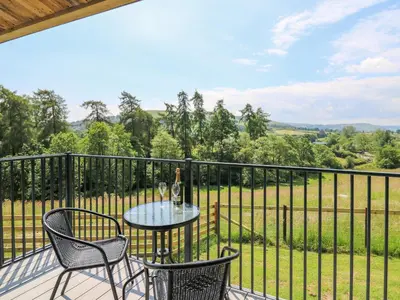a table and chairs on a balcony with a view of a field at Rooster's Rest in Saint Harmon