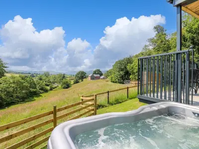 a hot tub on a balcony with a view of a field at Rooster's Rest in Saint Harmon