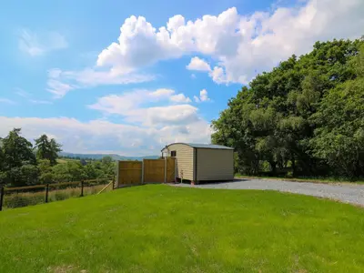 a small shed sitting on top of a grass field at Rooster's Rest in Saint Harmon