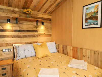 a bed in a room with a wooden wall at Rooster's Rest in Saint Harmon