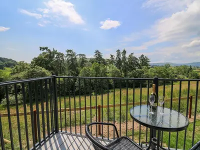 a table and chairs on a balcony with a view of a field at Hen's Hideaway in Saint Harmon