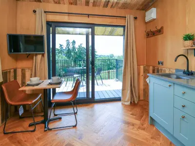a kitchen with a table and chairs and a balcony at Hen's Hideaway in Saint Harmon