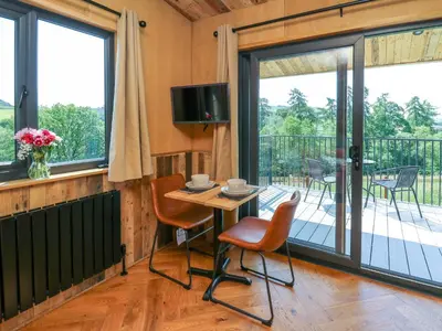 a room with a table and chairs and a balcony at Hen's Hideaway in Saint Harmon