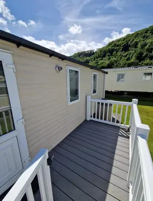 a house with a wooden deck next to a building at Cozy 2 Bedroom Static Caravan in Clarach Bay , Aberystwyth in Aberystwyth