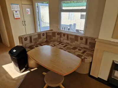 a room with a table and chairs and a fireplace at Cozy 2 Bedroom Static Caravan in Clarach Bay , Aberystwyth in Aberystwyth
