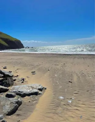 a sandy beach with rocks and the ocean at Cozy 2 Bedroom Static Caravan in Clarach Bay , Aberystwyth in Aberystwyth
