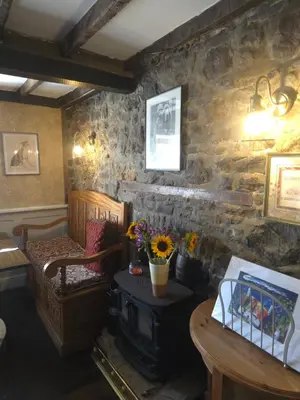 a living room with a stone wall with a wood stove at The Royal Oak Inn, Rhandirmwyn in Rhandirmwyn