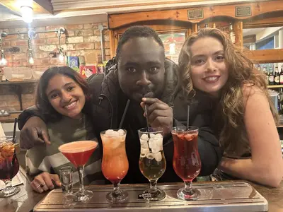 a group of three people sitting at a bar with drinks at The Pier Hotel in Aberystwyth
