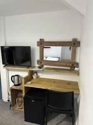 a wooden desk with a television and a chair at The Pier Hotel in Aberystwyth