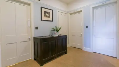 a hallway with two white doors and a wooden cabinet at Hafod Cae Maen in Penrhyndeudreath