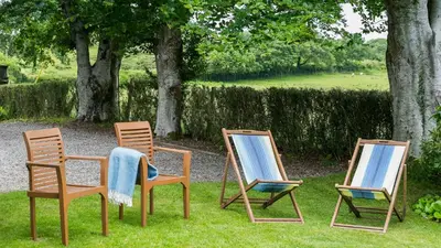 three chairs sitting in the grass in a yard at Hafod Cae Maen in Penrhyndeudreath