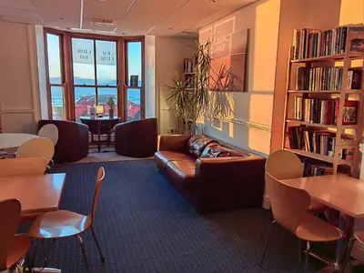 a library with a couch and a table and chairs at Cardigan and Celtic Bay Guest House - Self Catering Accommodation in Aberystwyth