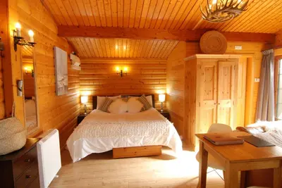 a bedroom with a bed in a wooden cabin at LARCHES LODGE Norwegian log cabin, wood stove & spa in Church Stretton