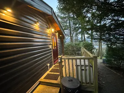 a porch of a house with a wooden door at LARCHES LODGE Norwegian log cabin, wood stove & spa in Church Stretton