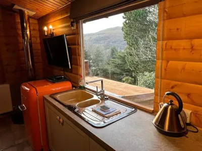 a kitchen with a sink and a window with a view at LARCHES LODGE Norwegian log cabin, wood stove & spa in Church Stretton