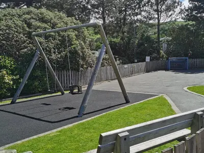 a swing set in a park with a fence at Snowdonia Holiday Sea Beach and Mountains view in Llwyngwril