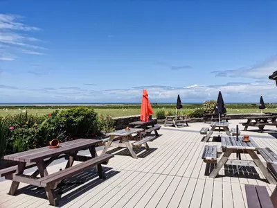 a row of picnic tables and umbrellas on a deck at Snowdonia Holiday Sea Beach and Mountains view in Llwyngwril