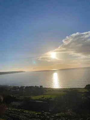 a view of the sun setting over the water at Ocean View with hot tub in Barmouth